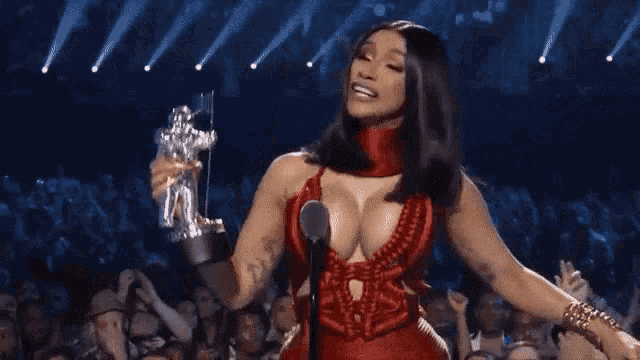 a woman in a red dress is holding a microphone and a trophy