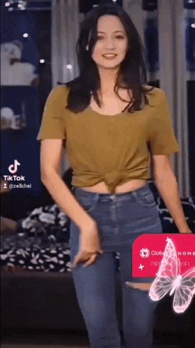 a woman in a yellow shirt and blue jeans is dancing in front of a globe card .