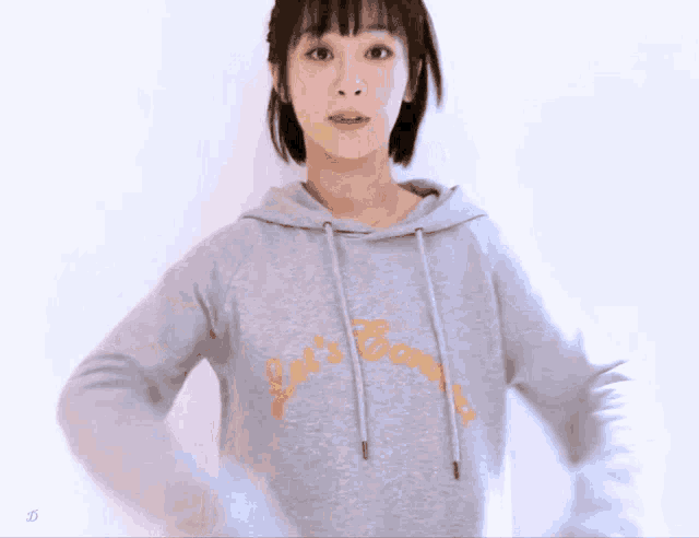 a woman wearing a grey hoodie that says let 's go