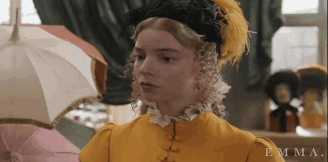 a woman wearing a yellow dress and a black hat with the name emma on the bottom