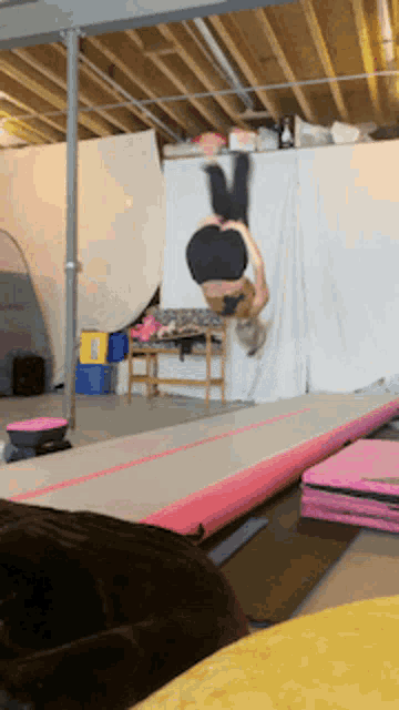 a person is doing a handstand on a pink mat in a gym