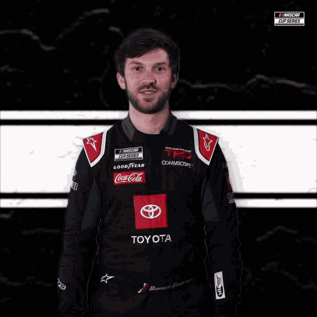 a man in a toyota racing suit is smiling for the camera