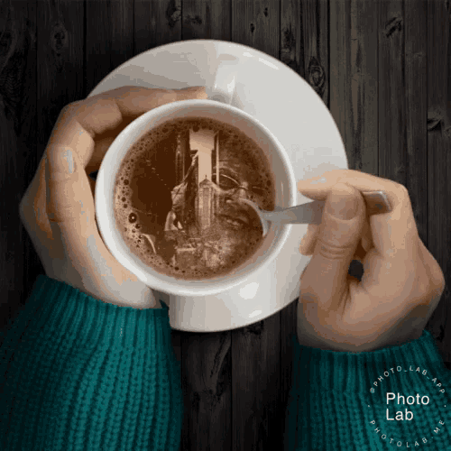 a person holding a cup of coffee with a spoon in their hands