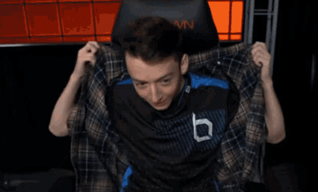 a young man is sitting in a gaming chair with his arms outstretched and smiling .
