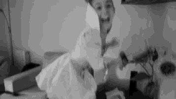 a black and white photo of a woman in a white dress holding a piece of paper