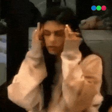a woman is holding her head with her hands in front of her face