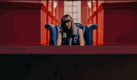 a woman is sitting in a blue leather chair in a hallway .