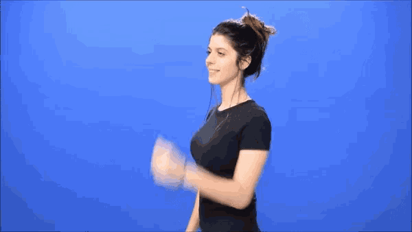 a woman wearing headphones and a black shirt is waving her hand in front of a blue background