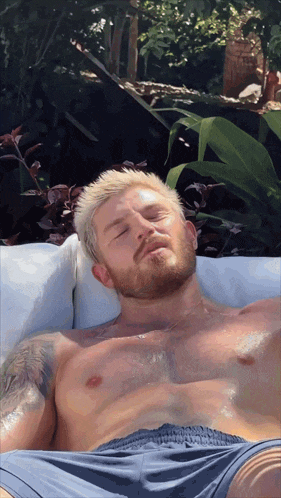 a shirtless man in blue shorts is laying on a couch