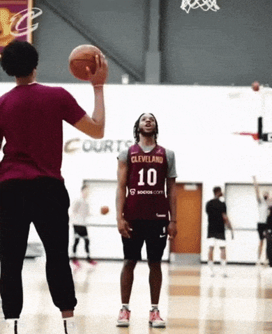 a man wearing a cleveland jersey is throwing a basketball to another man