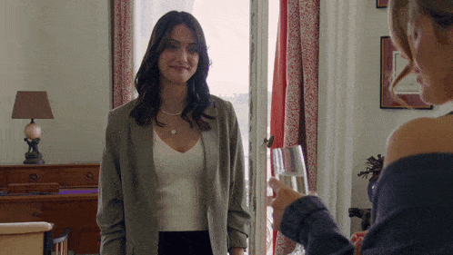 a woman holds a glass of wine while another woman looks on