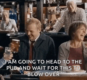 a man and a woman are sitting at a table in a pub holding beer glasses .