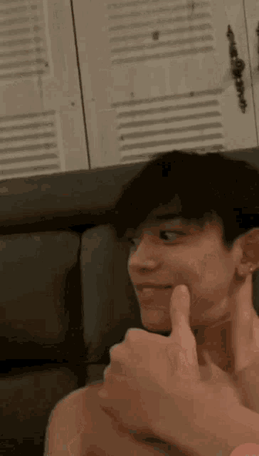 a shirtless man is giving a thumbs up sign while sitting on a couch