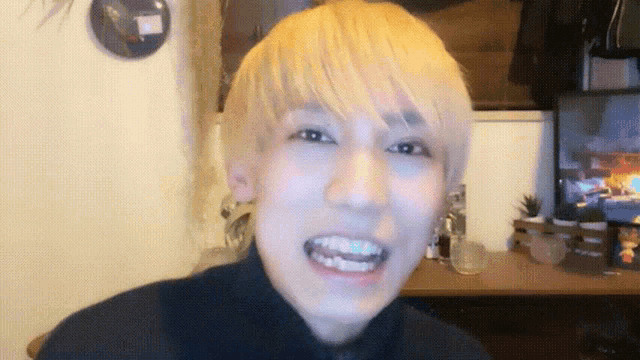a young man with blonde hair is smiling in front of a tv
