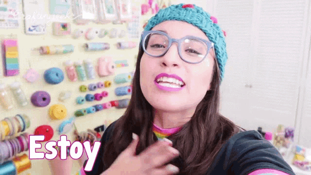 a woman wearing glasses and a knitted hat says estoy