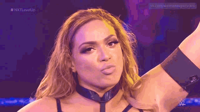 a female wrestler is making a funny face while wearing a choker .