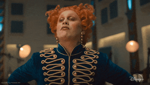 a woman with red hair is wearing a blue jacket with gold ropes
