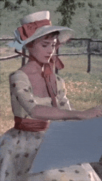 a woman wearing a white hat and a white dress is looking at a piece of paper
