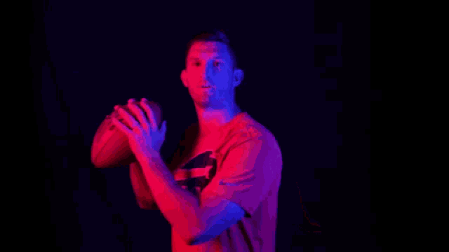 a man in a red shirt with a buffalo bills logo on it is holding a football