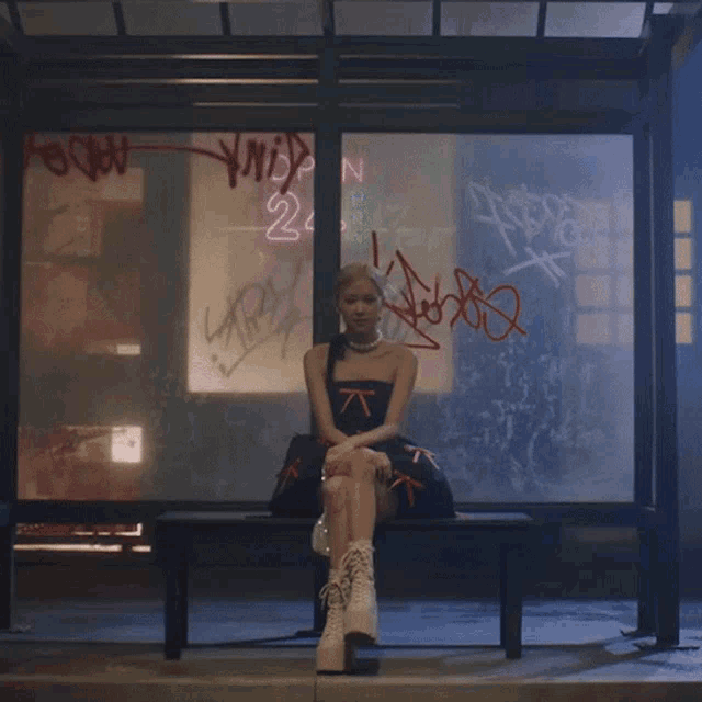 a woman sits on a bench in front of a window that has graffiti on it including the number 22