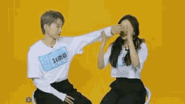 a man and a woman are sitting next to each other on a yellow background and smiling .