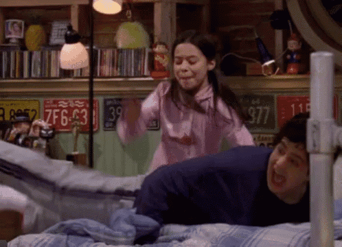 a girl in a pink shirt is standing next to a boy on a bed with a license plate that says 377