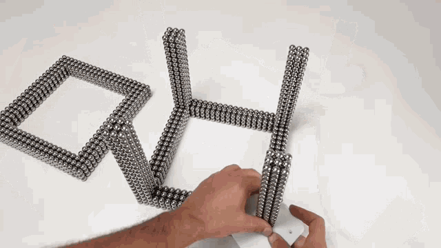a person is playing with magnetic balls on a white table