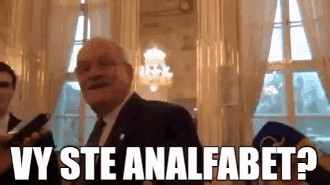 a man in a suit and tie is holding a microphone and says wy ste analfabet
