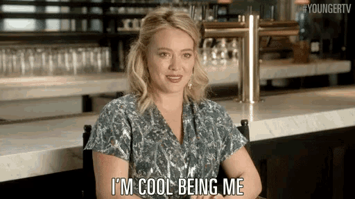 a woman is sitting at a bar and says i 'm cool being me .