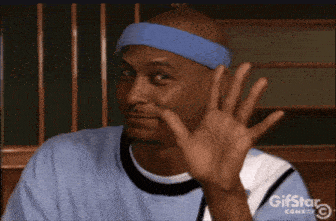 a man wearing a blue headband is waving his hand at the camera