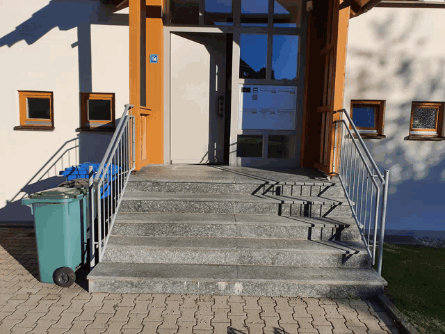 a green trash can sits in front of a building