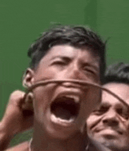 a man is screaming with his mouth open while another man is holding a wire around his neck .