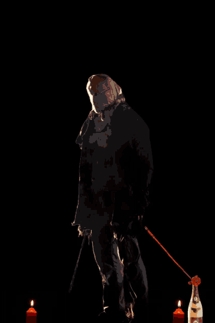 a man in a mask is standing next to a bottle of champagne and candles