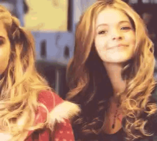 two women with long blonde hair are standing next to each other and smiling for the camera .