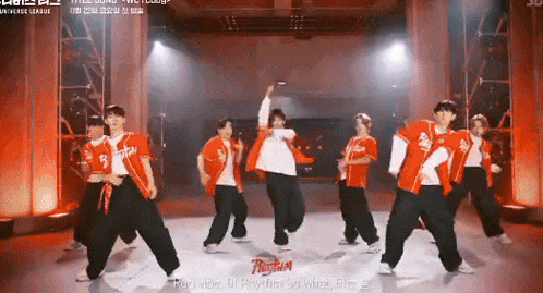 a group of young men are dancing on a stage in front of a sign that says rhythm .