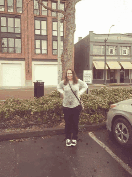 a woman stands in a parking lot with a sign that says no parking