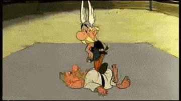 a cartoon character is laying on top of another cartoon character in a wrestling match .