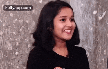 a young girl is smiling and looking at the camera .