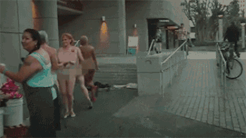 a naked man is giving a naked woman a rose in front of buckets of flowers