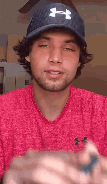 a man wearing a pink under armour shirt and a baseball cap