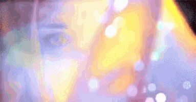 a close up of a woman 's face with a blurred background of lights behind her .