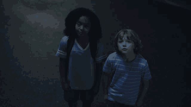 two children standing next to each other in the dark