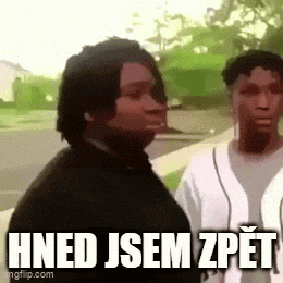two men are standing next to each other on a sidewalk with the words hned jsem zpet written above them .