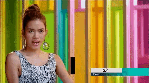 a woman is standing in front of a colorful wall with a sign that says teamu on it