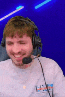 a man wearing headphones and a microphone is smiling while playing a video game .