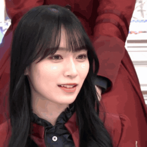 a close up of a woman 's face with a red jacket