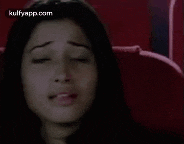 a woman is sitting in a red chair with her eyes closed and making a funny face .
