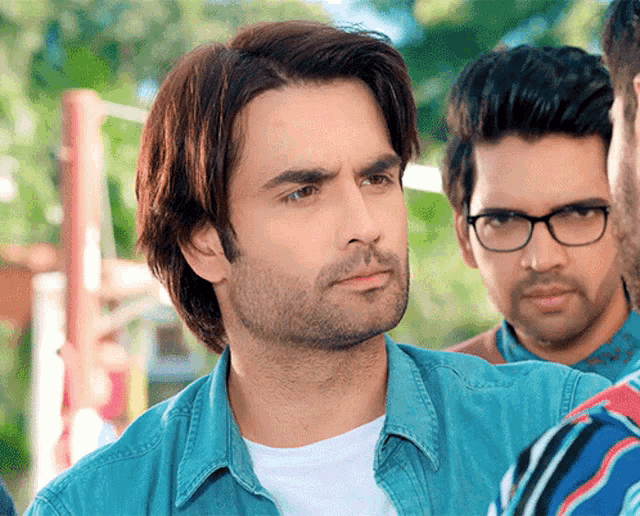a man wearing glasses and a blue shirt looks at something