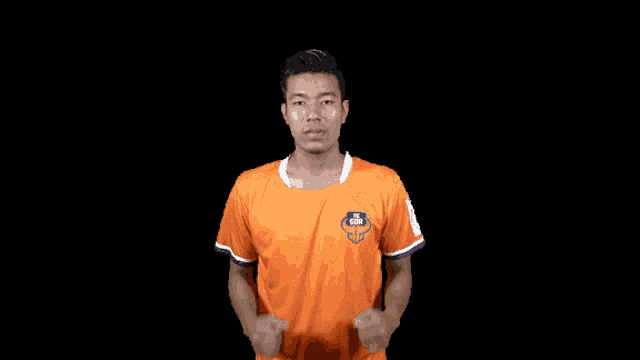 a man in an orange shirt has his fist in the air against a black background