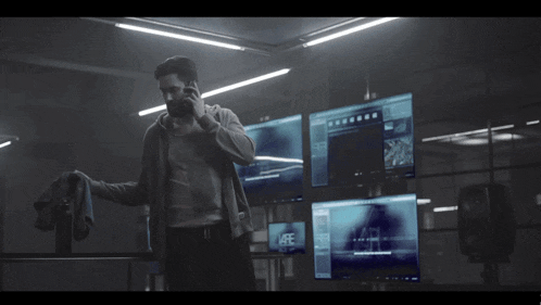 a man is talking on a cell phone in front of a monitor that says vare